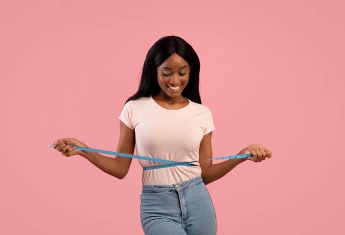 girl measuring reduced belly fat